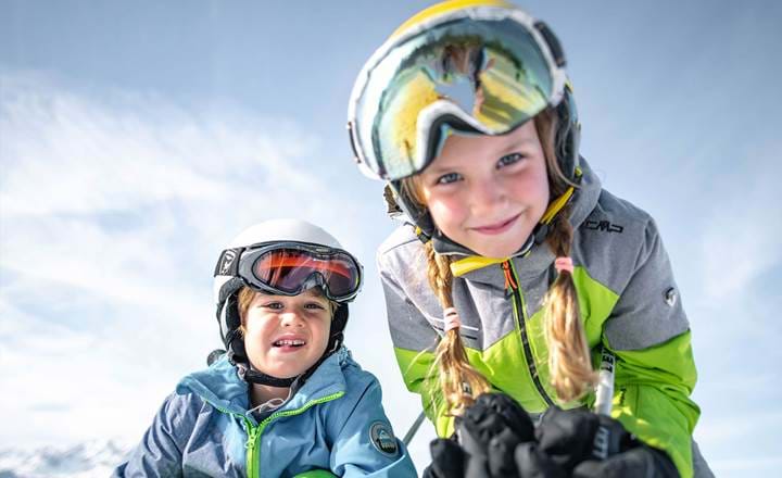 Glade børn med skiudstyr kigger i kameraet i Alpendorf
